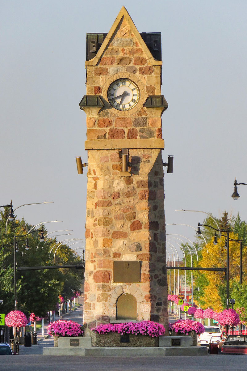 the wainwright clock located in the central Wainwright historic district, with pink flowers in beds in the foreground