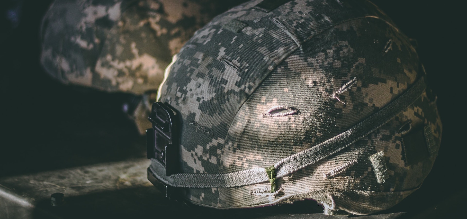 a shadowed side view of a camouflage soldier defence helmet