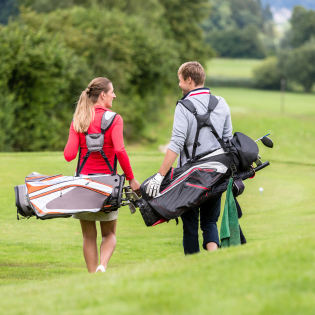 two golfers carrying golf bags on the greens